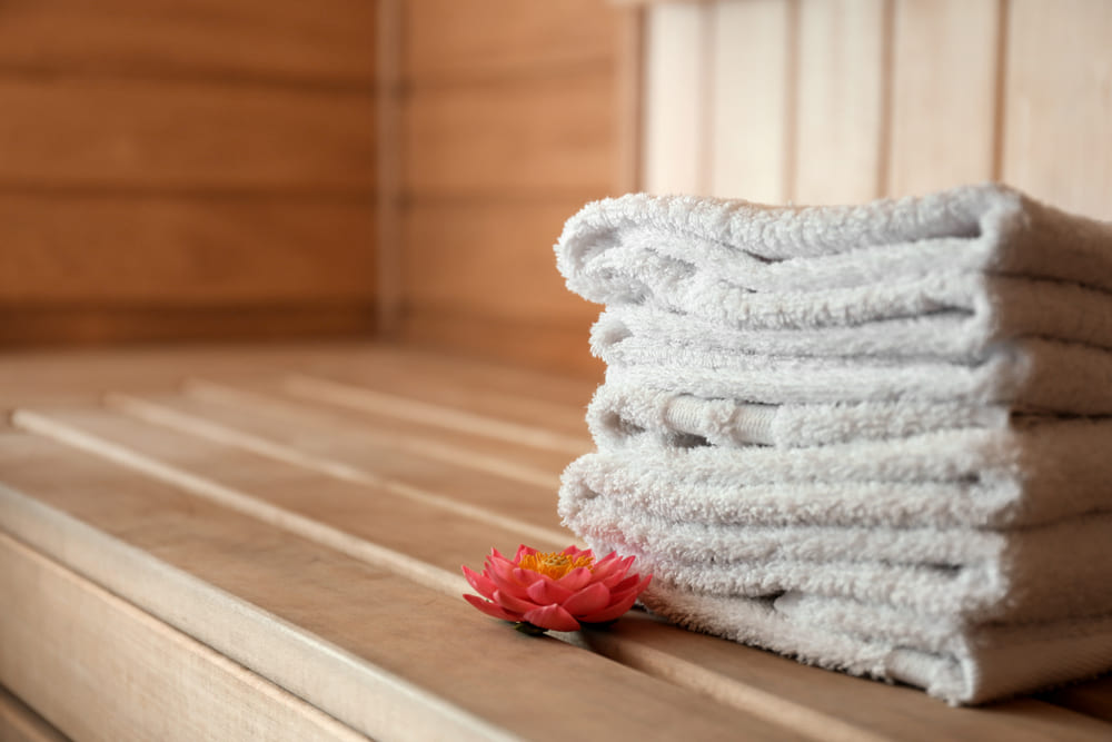 Stack of towels on wooden bench in sauna