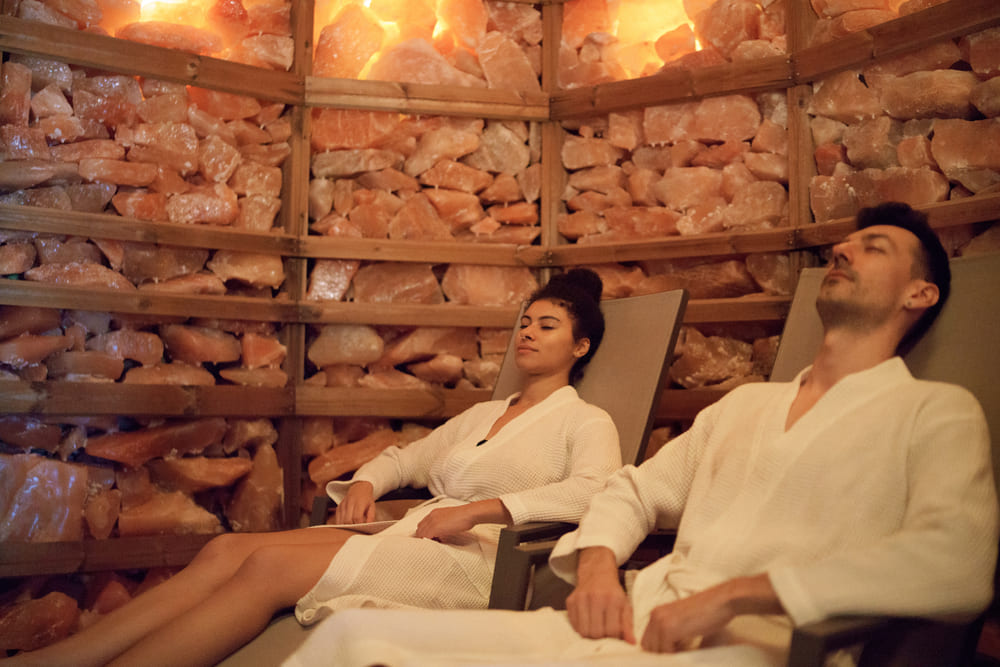 Portrait of young couple in salt inhalation steam room, relaxing.
